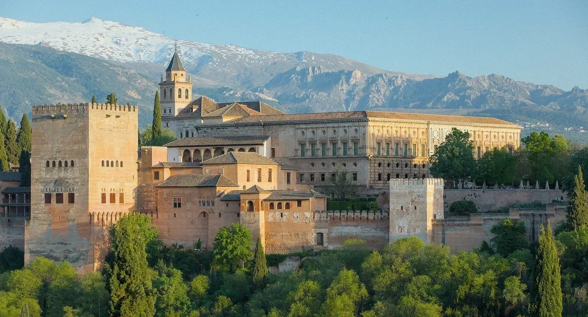 The Alhambra palace walls and towers seen across the Darro valley at sunset from the San Nicolás viewpoint in Granada, Spain