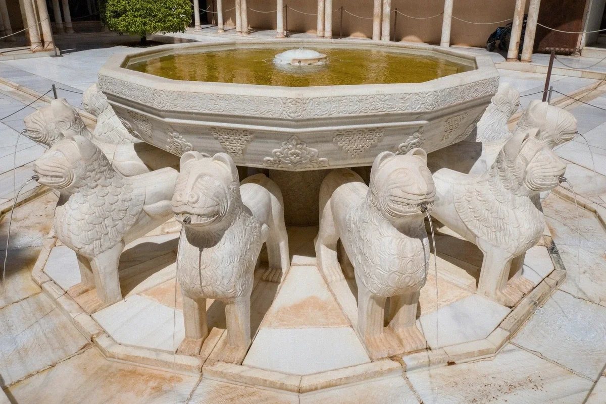 The fountain of the Court of the Lions lit at night in the Nasrid Palaces, Alhambra, Granada