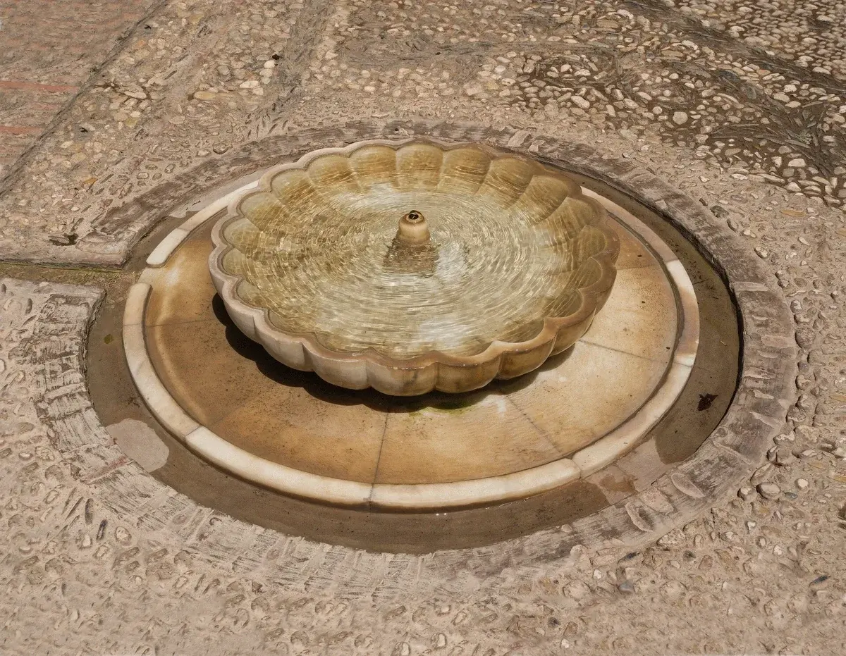 Visitors resting by a fountain in the Generalife gardens at the Alhambra, Granada