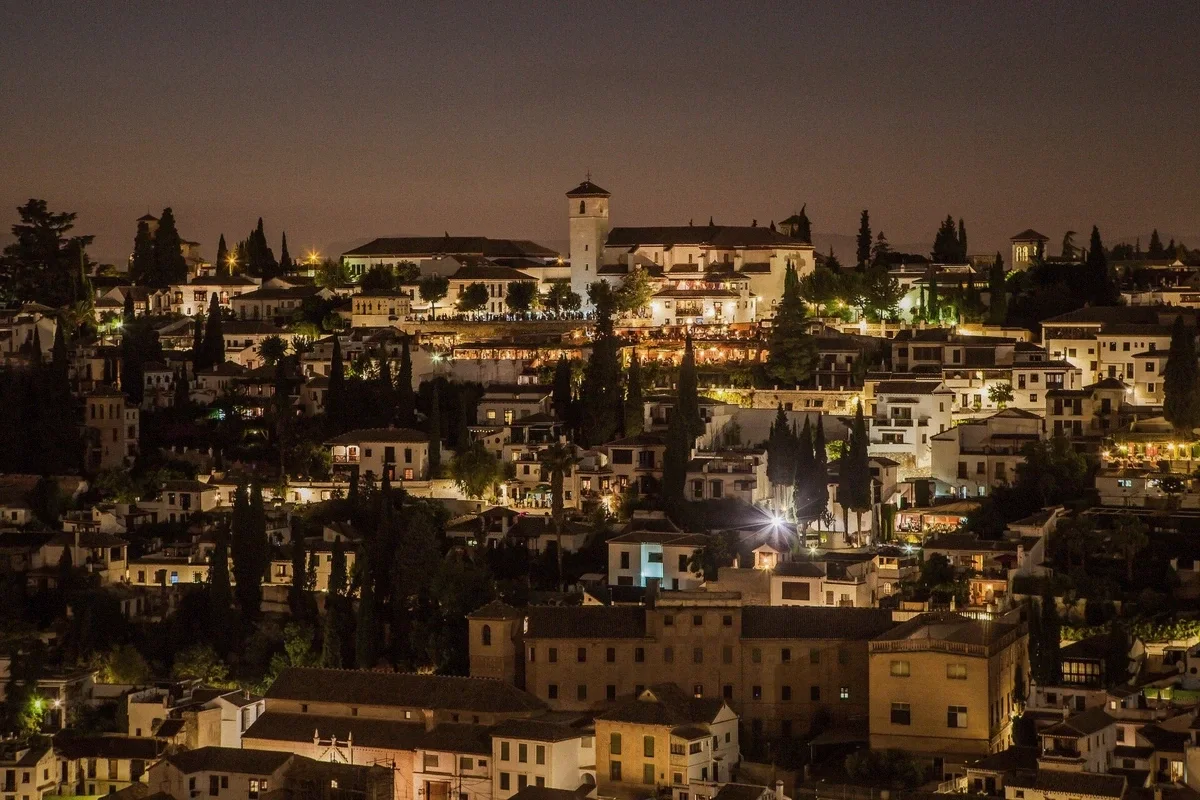 The Alhambra’s towers lit at night seen from across the Darro valley, Granada, Spain