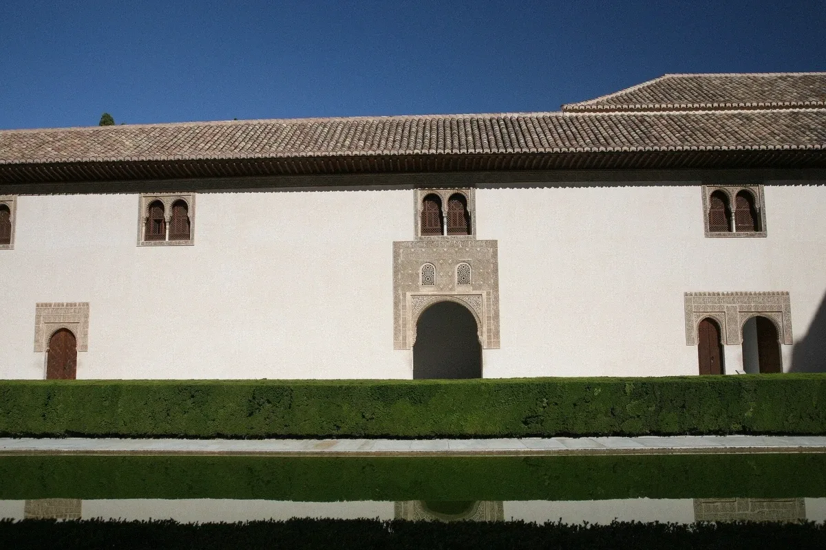 Nasrid Palaces arches reflected in the Court of the Myrtles pool on a private Alhambra tour in Granada, Spain